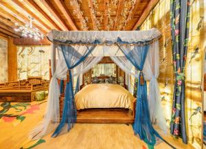 Lijiang Shuhe Zuo'an Inn في ليجيانغ: غرفة نوم مع سرير مظلة مع ستائر زرقاء