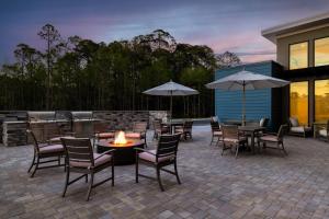 un patio con tavoli, sedie e ombrelloni di Residence Inn Panama City Beach Pier Park a Panama City Beach