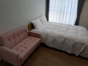 una camera da letto con un letto, un divano e una finestra di 石巻宿 a Ishinomaki