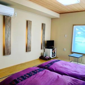 a bedroom with a large purple bed and a tv at KAZEMACHIOYADO RAMUYA 〜風待ち御宿　来夢や〜 in Shimoda