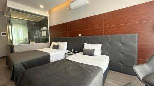ハノイにあるMango Hotel - Ha Noi Railway stationのベッド2台と鏡が備わるホテルルームです。