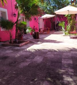 Casa Isabella في كوزوميل: مبنى وردي مع طاولات ومظلات في ساحة الفناء