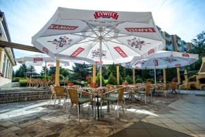 een patio met tafels en stoelen met parasols bij Hotel Pietrak in Trzemeszno +33 foto's