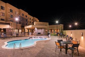einen Pool in der Nacht mit Stühlen und einem Tisch in der Unterkunft Courtyard by Marriott Jacksonville in Jacksonville