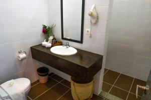 a bathroom with a sink and a toilet and a mirror at Balibo Fort Hotel in Balibo