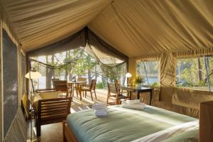 Zelt-Schlafzimmer mit einem Bett, einem Tisch und Stühlen in der Unterkunft Tanja Lagoon Camp in Tanja