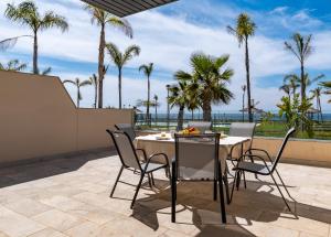un patio con mesa, sillas y palmeras en El amanecer, Apartamento 1 linea de playa en Vélez-Málaga