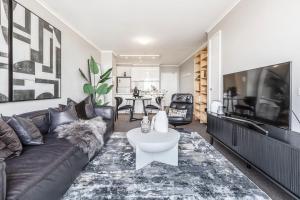 uma sala de estar com um sofá e uma televisão em VAQUAY Enigma In Southbank em Melbourne