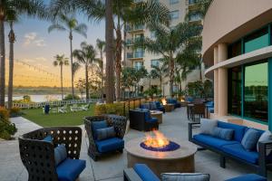 eine Terrasse mit Stühlen und eine Feuerstelle mit Palmen in der Unterkunft Newport Beach Marriott Bayview in Newport Beach