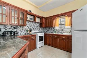 a kitchen with wooden cabinets and a white stove top oven at Kaibus Place K3 2/bedroom in Morne Rouge +21 photos