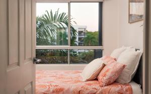 1 dormitorio con cama con almohadas y ventana en Tropical Bliss in Woolner, en Stuart Park