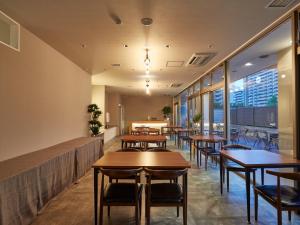泉佐野市にあるEZ HOTEL 関西空港 Seasideの木製のテーブルと椅子、窓のあるレストラン