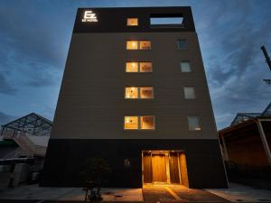 un edificio alto de color negro con luces en las ventanas en EZ HOTEL 関西空港 Seaside en Izumi-Sano