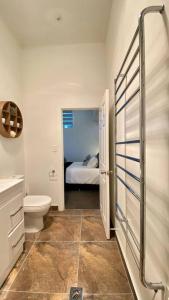 a bathroom with a toilet and a bed in a room at The Statesman in Hamilton