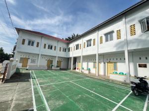 a building with a tennis court in the courtyard at Guesthouse Ananda Lubuk Basung in Ambacauggatal