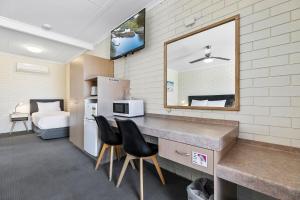 a room with a kitchen with a counter and chairs at Comfort Inn on Main Hervey Bay in Hervey Bay