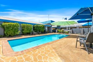 una piscina con sillas y sombrillas junto a un edificio en Comfort Inn on Main Hervey Bay en Hervey Bay