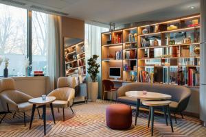 biblioteca con mesas, sillas y estanterías en AC Hotel Paris Porte Maillot by Marriott, en París