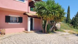 a pink house with palm trees in front of it at Thanos home corfu in Kynopiástai