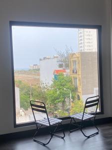 due sedie sedute davanti a una grande finestra di Nhật Quang House 2 a Da Nang