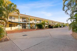 an exterior view of a building with palm trees at Arlia Sands Apartments in Hervey Bay