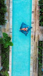 a person laying in a raft in a swimming pool at Casa Kapuas in Gili Trawangan