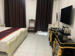 Habitación de hotel con cama y escritorio con TV. en CHALEUNXAY HOTEL en Vientián