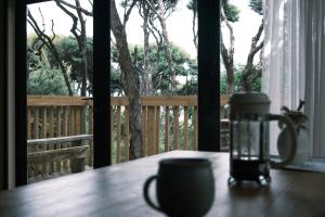 a table with a cup and a candle on a balcony at Modern, Cosy Hideaway - Rua Nuka Raglan in Raglan