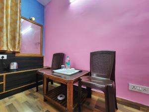 una mesa y sillas en una habitación con una pared rosa en Hotel Tirupati Regency Anandam en Shimla