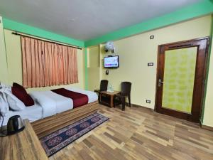 1 dormitorio con 1 cama, TV y puerta en Hotel Tirupati Regency Near Mall Road en Shimla