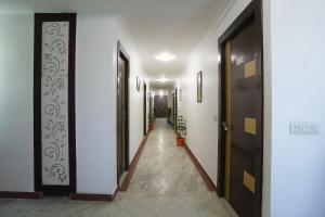un pasillo con paredes blancas y puertas negras en FabHotel BR International en Agra