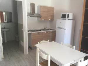 a kitchen with a table and a white refrigerator at Duna camere con bagno in Lido Adriano
