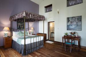 ein Schlafzimmer mit einem Himmelbett und Holzboden in der Unterkunft King's Cliff in Udagamandalam