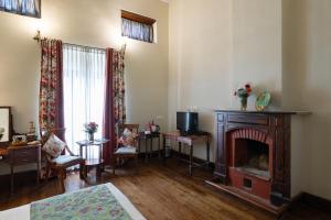 salon z kominkiem i łóżkiem w obiekcie King's Cliff w mieście Utakamand