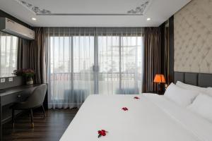 Habitación de hotel con cama blanca grande y escritorio. en Avani Central Hotel, en Hanói