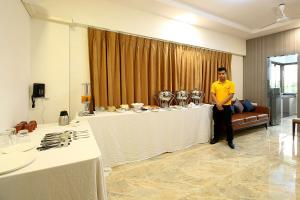 a man is standing next to a long table at Mumbai House Luxury Apartments Santacruz East, Mumbai in Mumbai