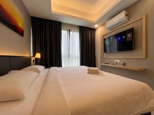 a bedroom with a white bed with a flat screen tv at QUINCE HOME GRAND ION DELEMEN GENTING HIGHLANDs in Genting Highlands
