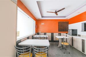 comedor con paredes de color naranja, mesas y sillas en FabHotel VRJ Residency, en Chennai