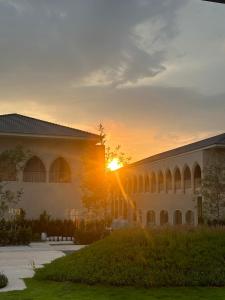 a building with the sun setting behind it at Navakiri Boutique Resort Satun in Ban Khuan