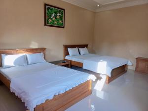 a bedroom with two beds with white sheets at Nusawiru Guest House in Pangandaran