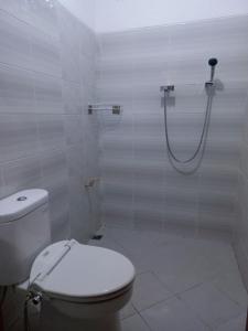 a white bathroom with a toilet and a shower at Nusawiru Guest House in Pangandaran