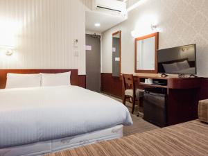 a hotel room with a bed and a desk and a television at Hotel Hillarys in Osaka