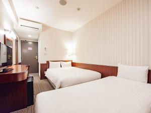 a hotel room with two beds and a desk at Hotel Hillarys in Osaka