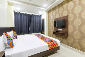 een slaapkamer met een wit bed en een televisie bij FabHotel The Kumar Inn in Patna