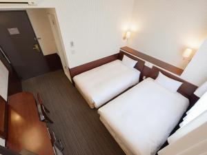 a small room with two beds and a desk at Hotel Hillarys in Osaka