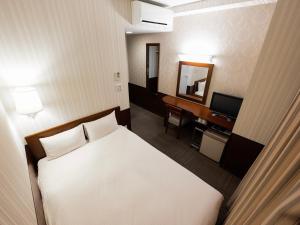 a bedroom with a bed and a desk with a mirror at Hotel Hillarys in Osaka