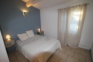 a bedroom with a white bed and two tables with lamps at Le gîte des Limites in Rognonas