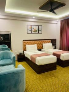 a hotel room with two beds and a chair at VOVO HOTELS in Yelahanka