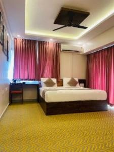 a bedroom with a large bed and pink curtains at VOVO HOTELS in Yelahanka