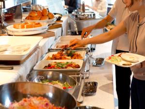 two people preparing food in a buffet line at Hotel Hillarys in Osaka